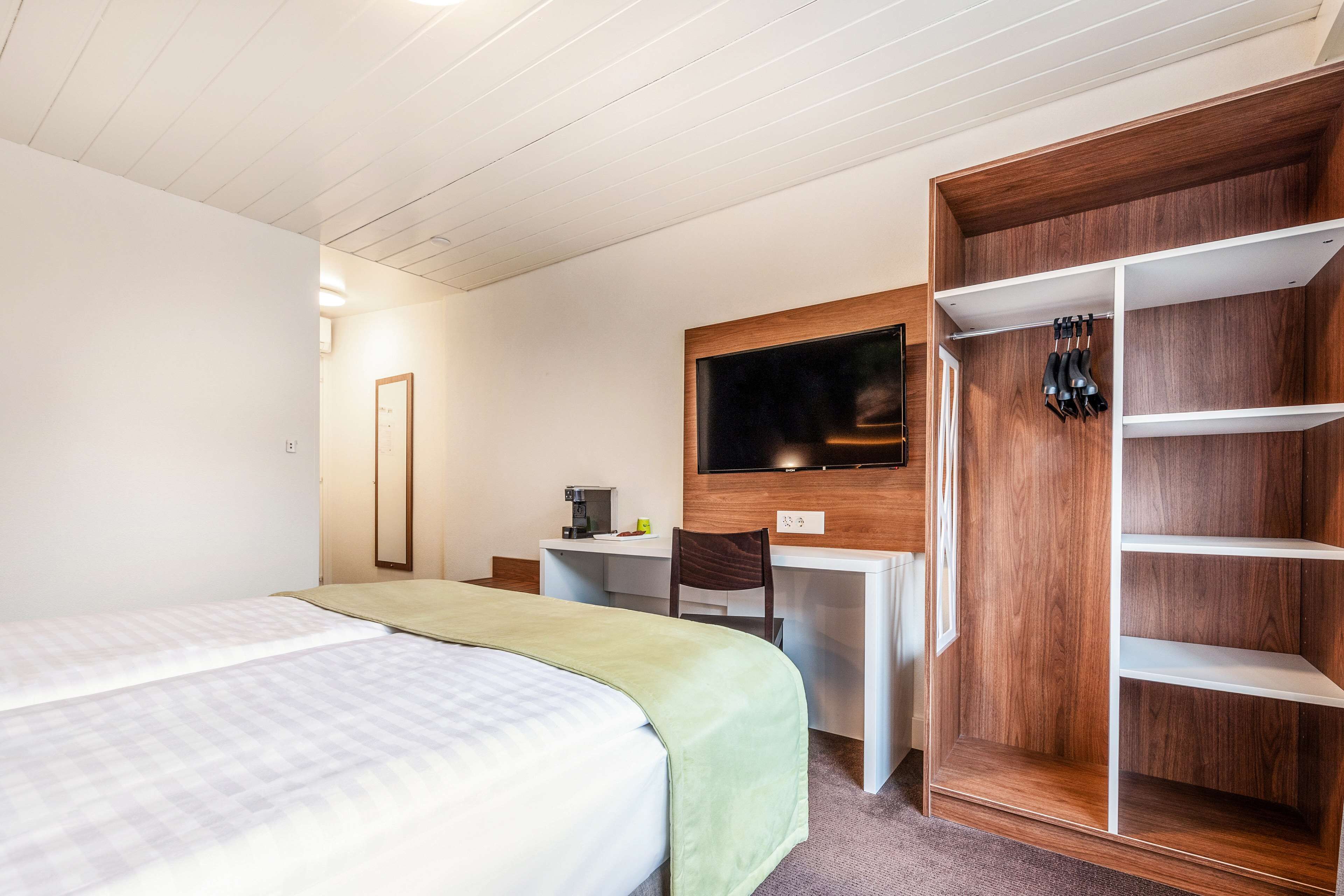 Een hotelkamer met twee bedden, een bureau, een televisie en een kledingkast.