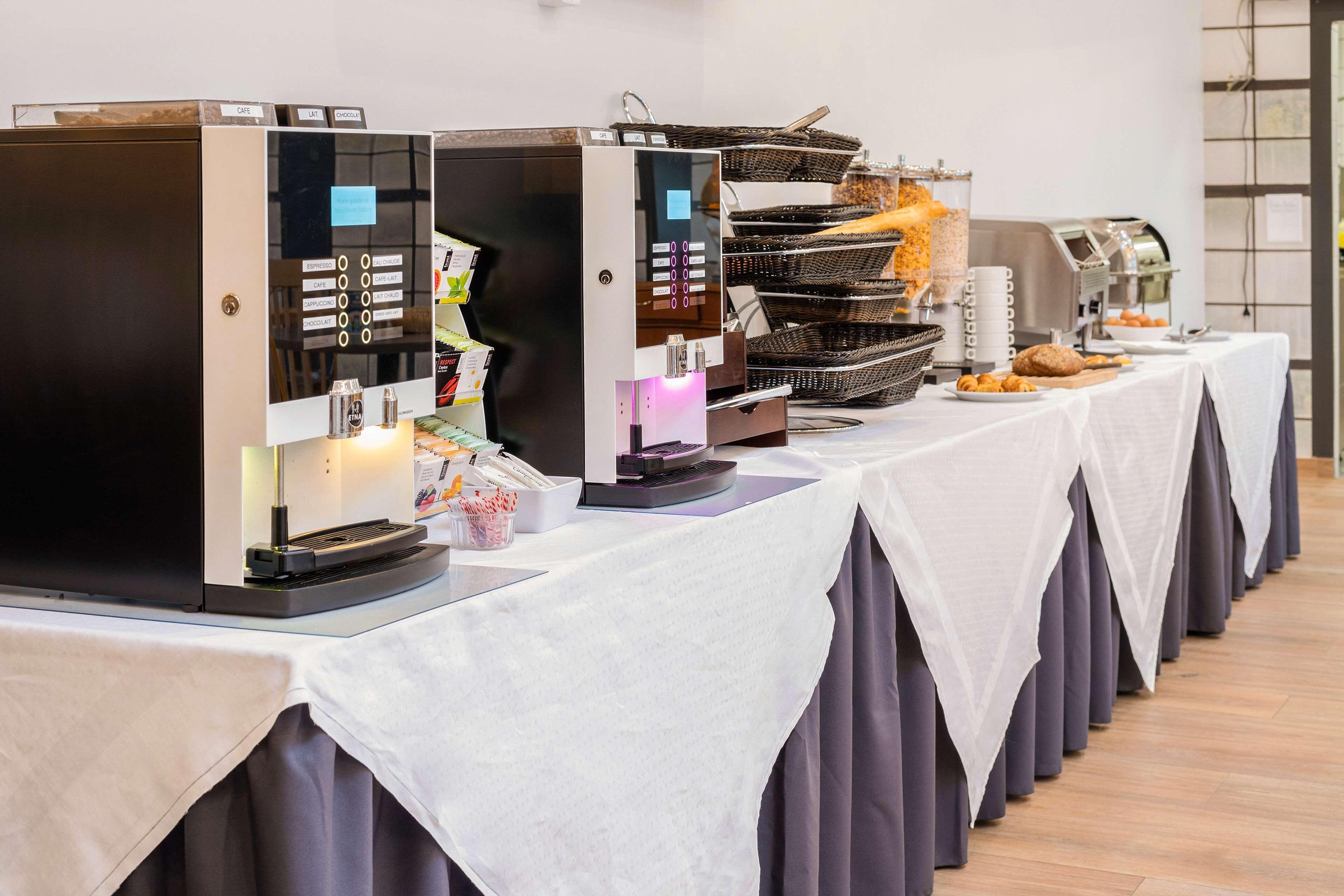 A buffet setup with multiple coffee machines and a variety of food items.