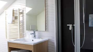 Un baño moderno con ducha de vidrio, lavabo blanco y tocador de madera.