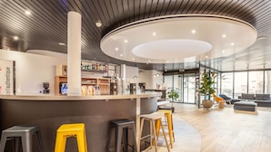 A modern bar area with stools, a counter, and a large circular ceiling light. - Campanile Martigny (Martigny)