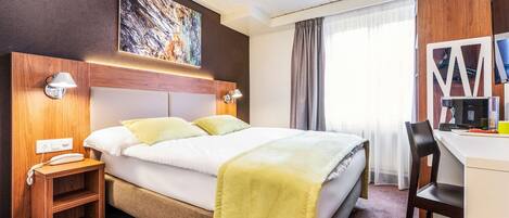 Una habitación de hotel con cama, lámparas de noche, escritorio y una silla.