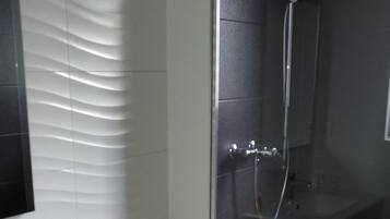 Een badkamer met een wit toilet, een glazen douchecabine en een witte wastafel met een houten kast eronder.
