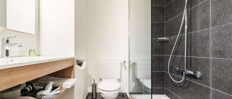 Un baño moderno con inodoro, lavamanos y ducha.