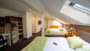 A hotel room with two beds, a desk, a wardrobe, and a skylight.