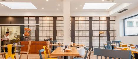 Un comedor moderno con mesas redondas, sillas e iluminación colgante.