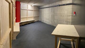 A room with a concrete floor, wooden panel walls, a red accent wall, and a small table.