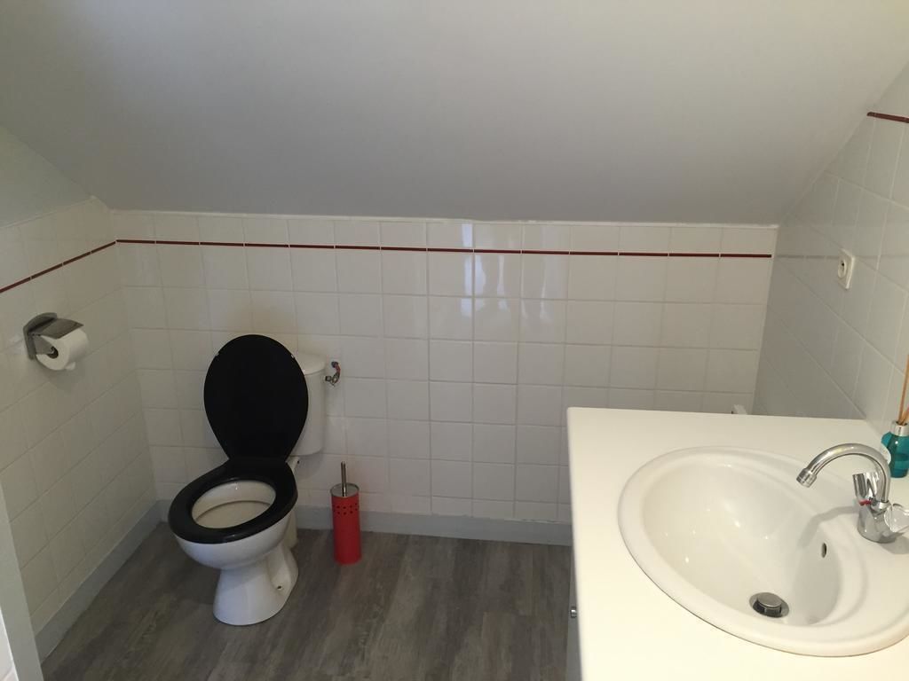 Une salle de bain avec des toilettes, un lavabo et des murs carrelés.