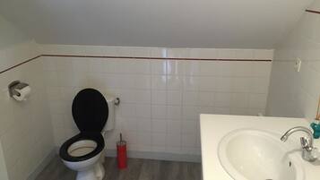 Une salle de bain avec des toilettes, un lavabo et des murs carrelés.