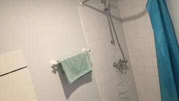 Ducha con cortina azul, toallero con una toalla azul claro y radiador blanco.