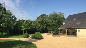 A gravel driveway leading to a building with a stone facade and a covered patio area. - Domaine des Mille Oiseaux - Colibris (Villiers-Charlemagne)