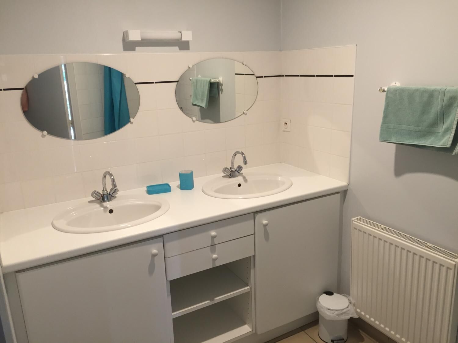 Une salle de bain avec deux lavabos, un miroir, un porte-serviettes et des toilettes.