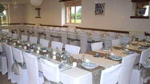 A banquet hall with long tables set for a formal event, white chairs with silver sashes, and a neutral color scheme. - Domaine des Mille Oiseaux - Colibris (Villiers-Charlemagne)