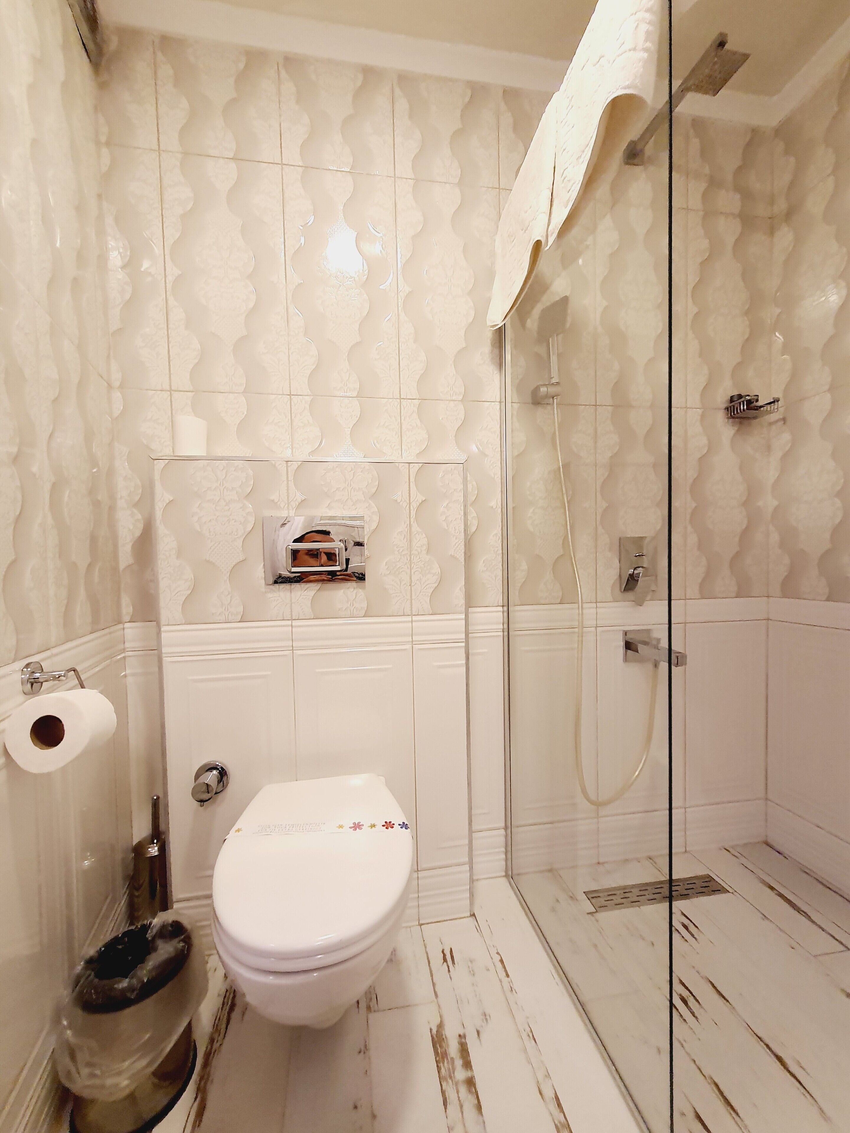 A bathroom with a toilet, a shower, and a toilet paper holder.