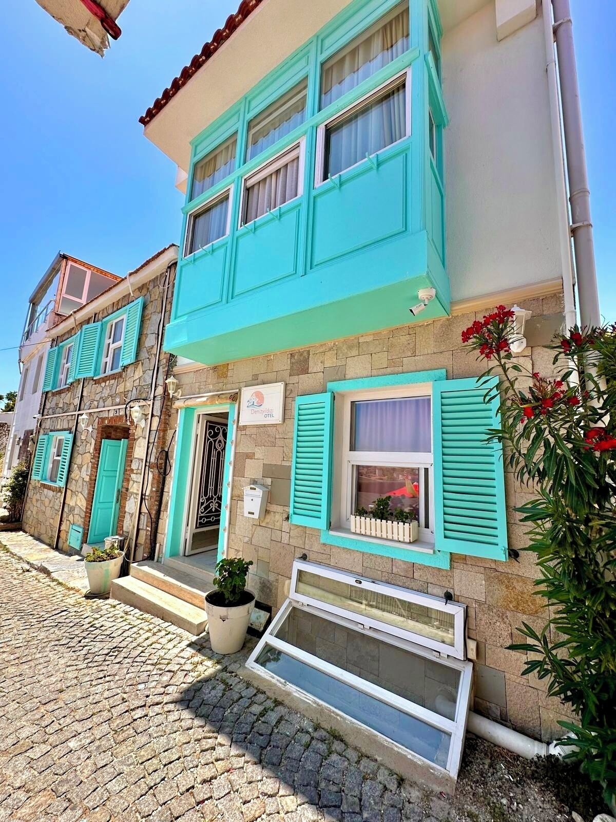 A building with a stone facade, turquoise shutters, and a sign indicating a hotel.