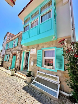 A building with a stone facade, turquoise shutters, and a sign indicating a hotel. - Bozcaada Denizyildizi Otel (Bozcaada)