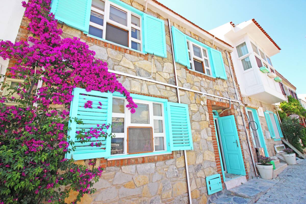 Un edificio de piedra con contraventanas turquesa y un balcón.