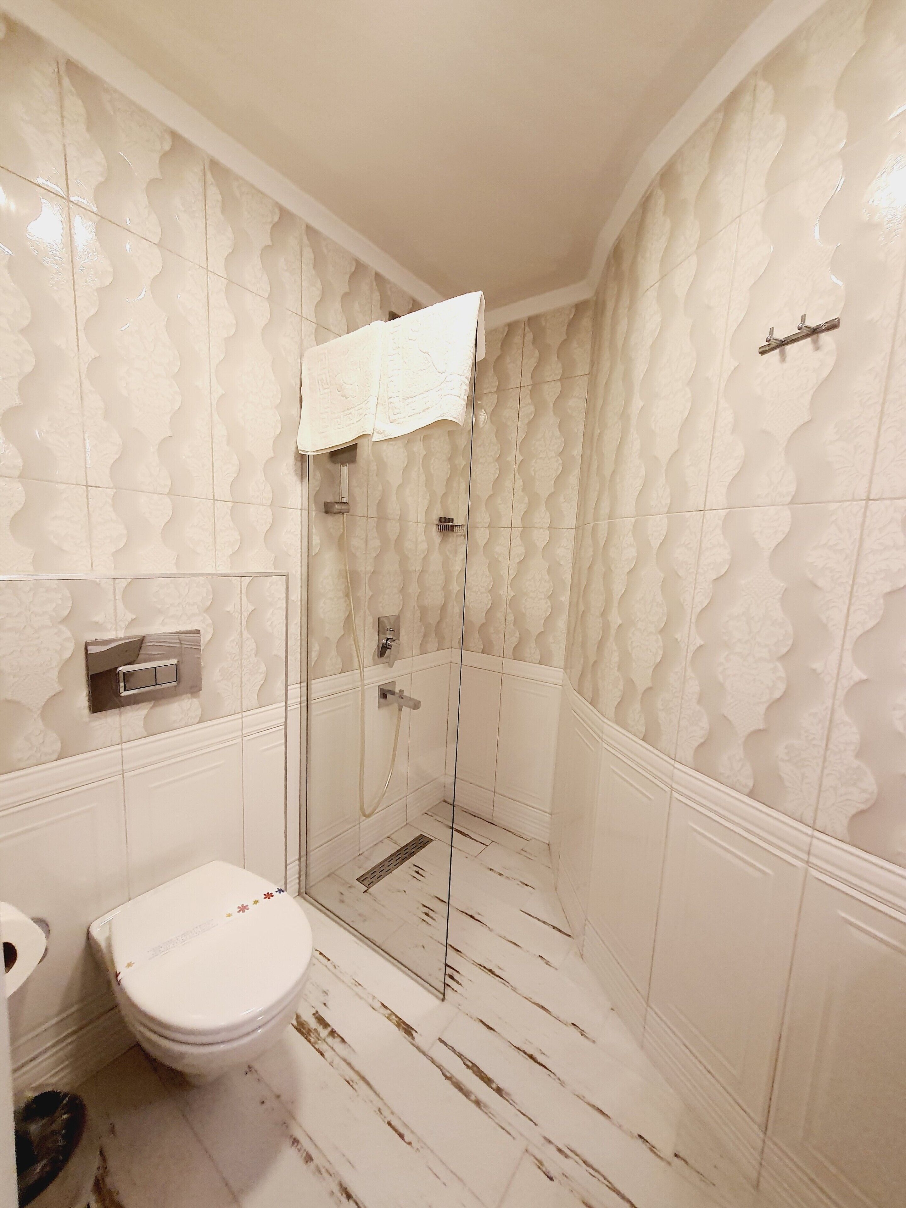 A bathroom with a shower, toilet, and a towel rack.