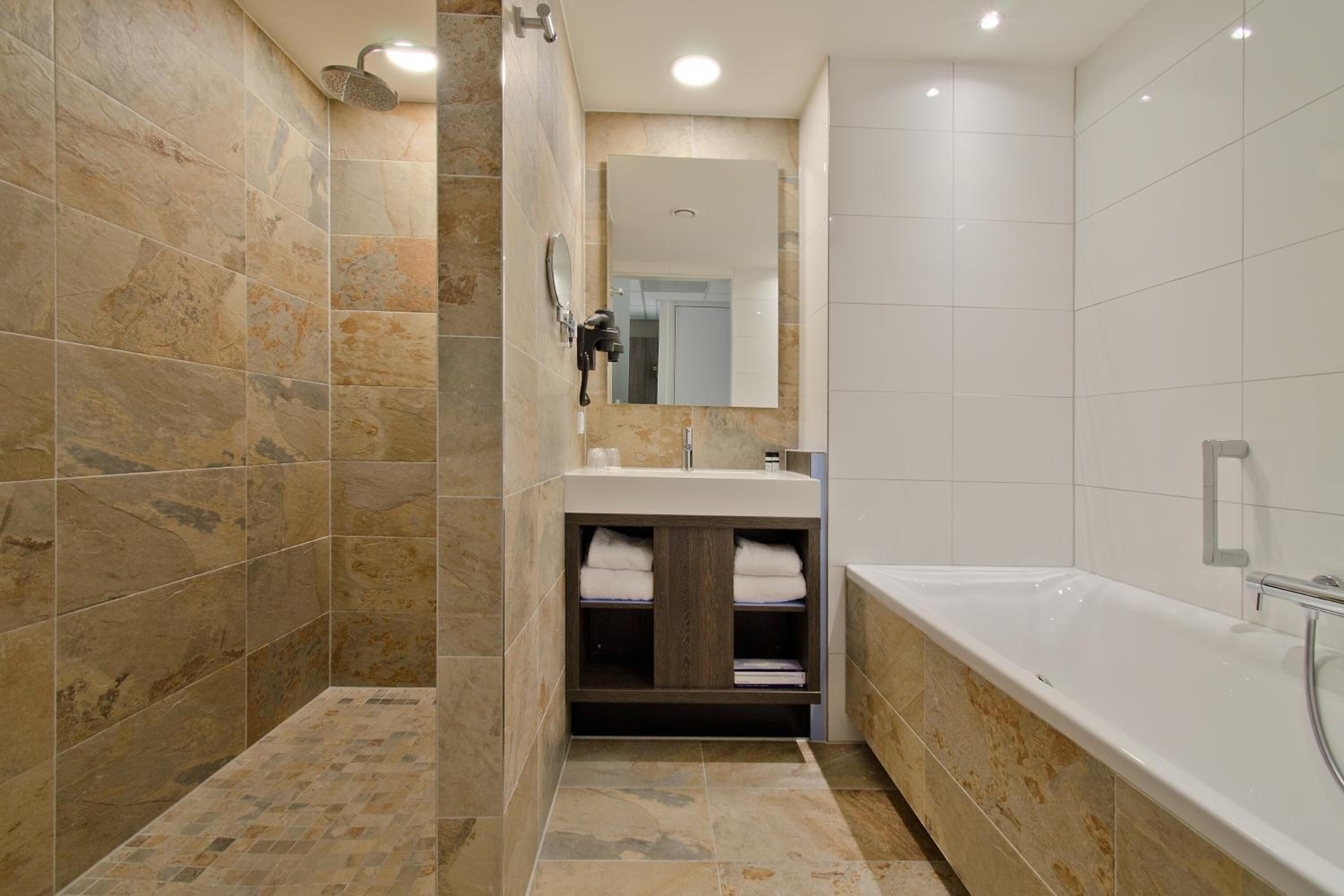 A modern bathroom with a shower, sink, and bathtub.