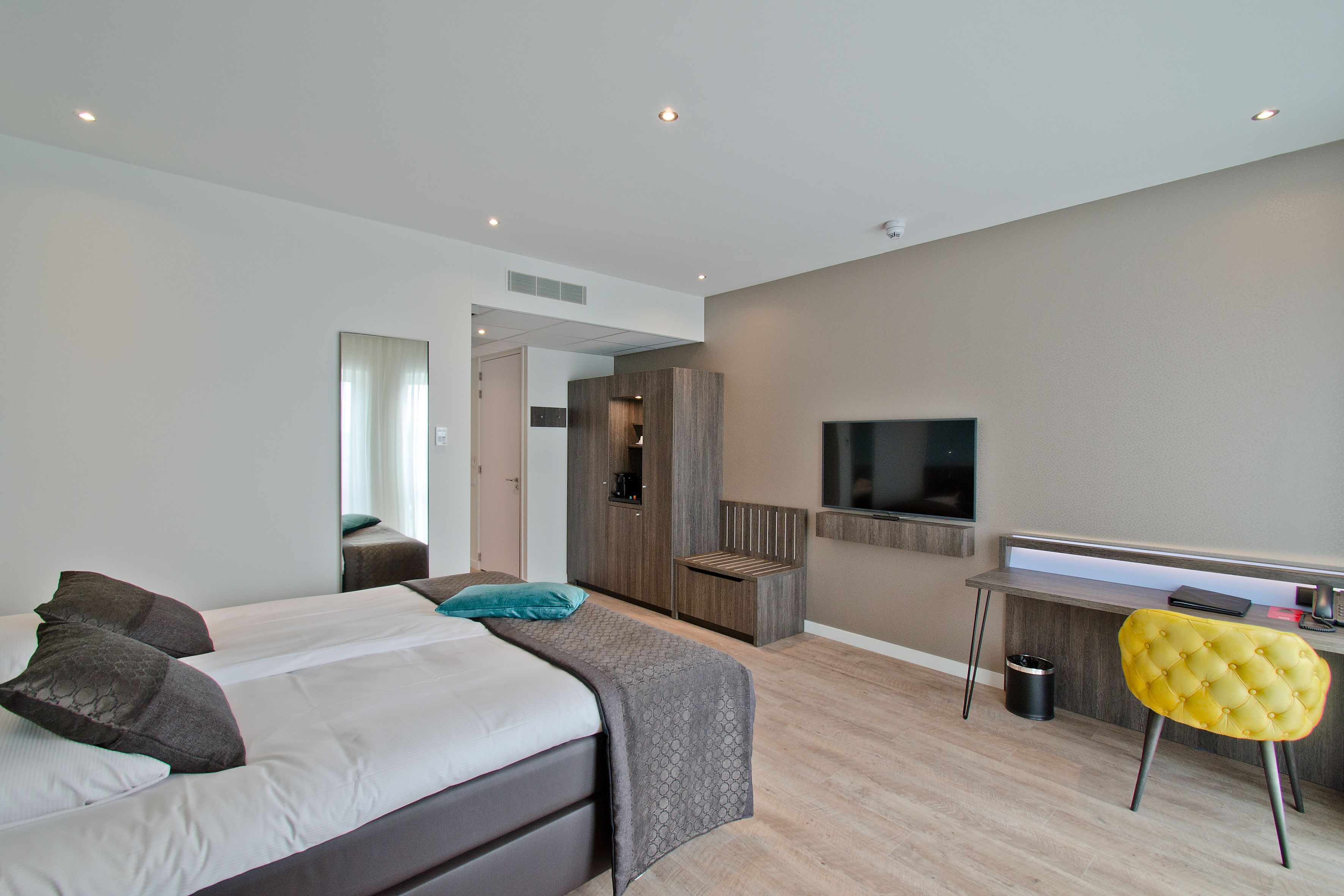 Ein modernes Hotelzimmer mit einem großen Bett, einem Schreibtisch, einem Fernseher und einer kleinen Sitzecke.
