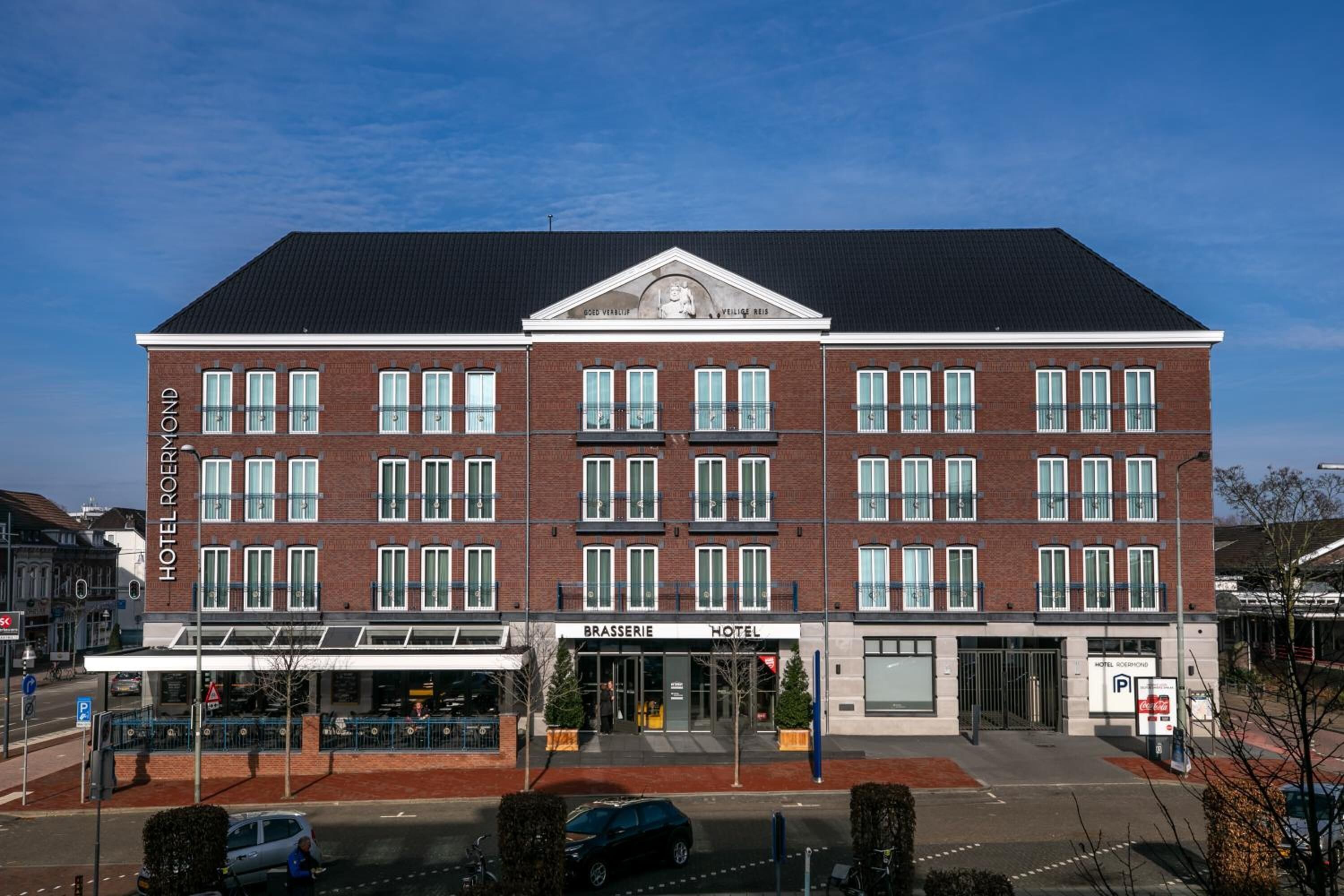 Een hotel met een symmetrische gevel, veel ramen en een centrale ingang.