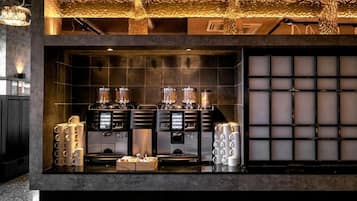 Um café com máquinas de expresso, um moedor e uma variedade de chávenas de café.