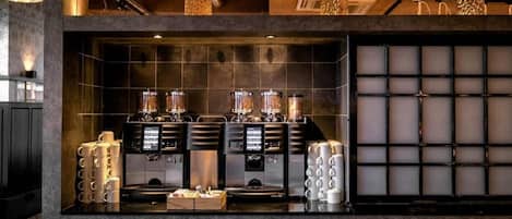 Una cafetería con máquinas de espresso, un molinillo y una exhibición de tazas de café.