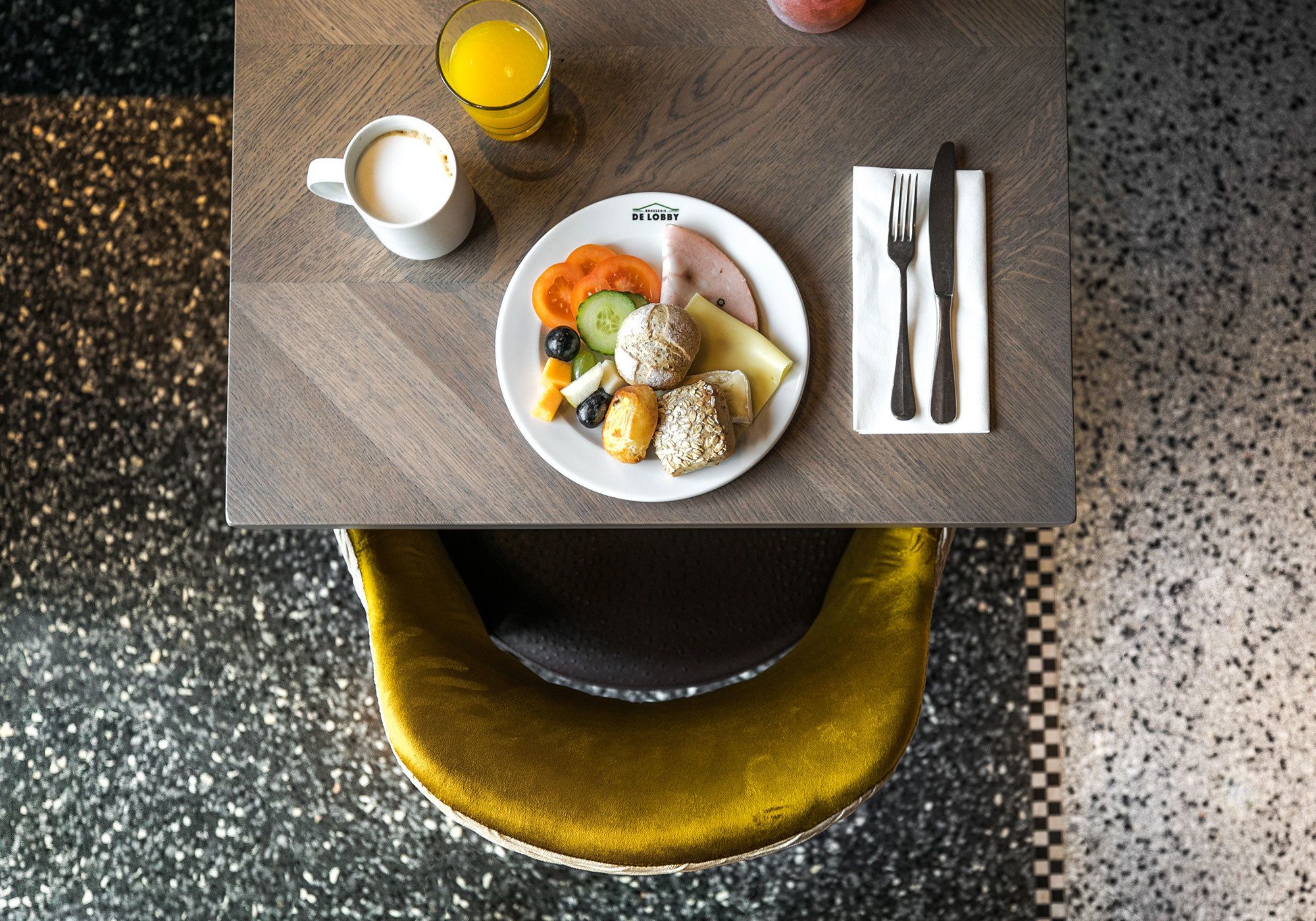 A breakfast table with a plate of food, a cup of coffee, and a glass of orange juice.