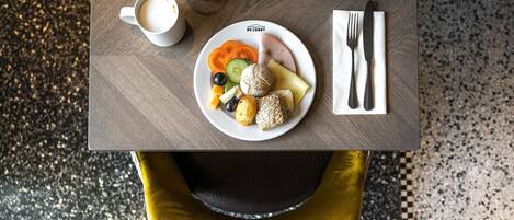 A breakfast table with a plate of food, a cup of coffee, and a glass of orange juice.