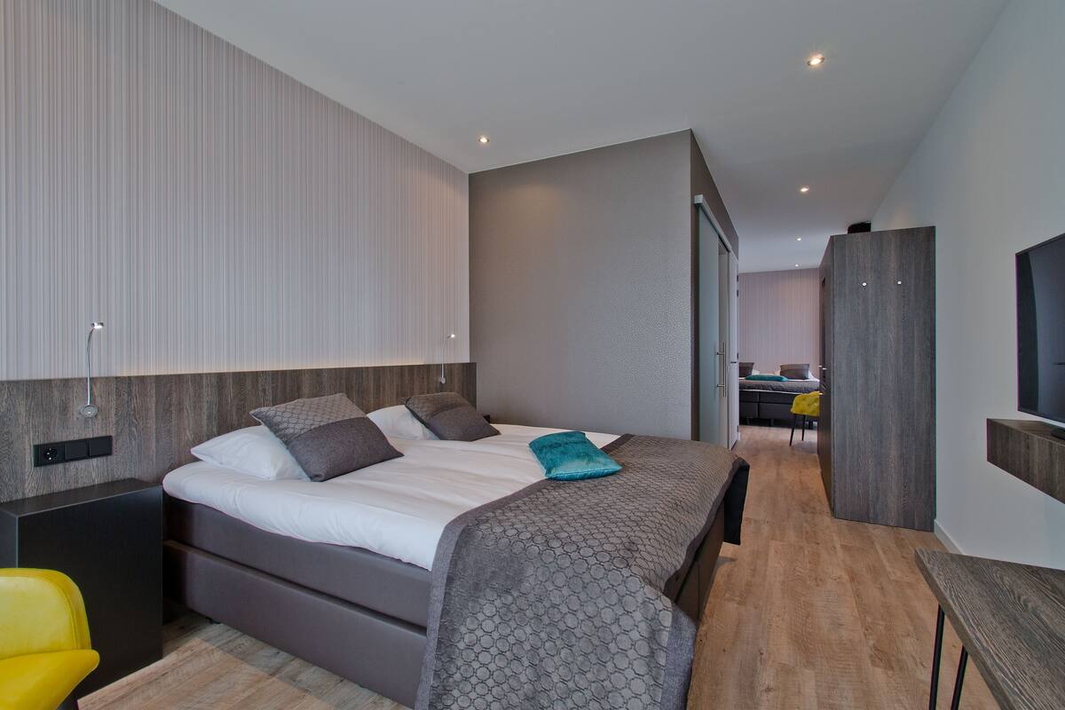 A modern hotel room with a large bed, a desk, and a chair.