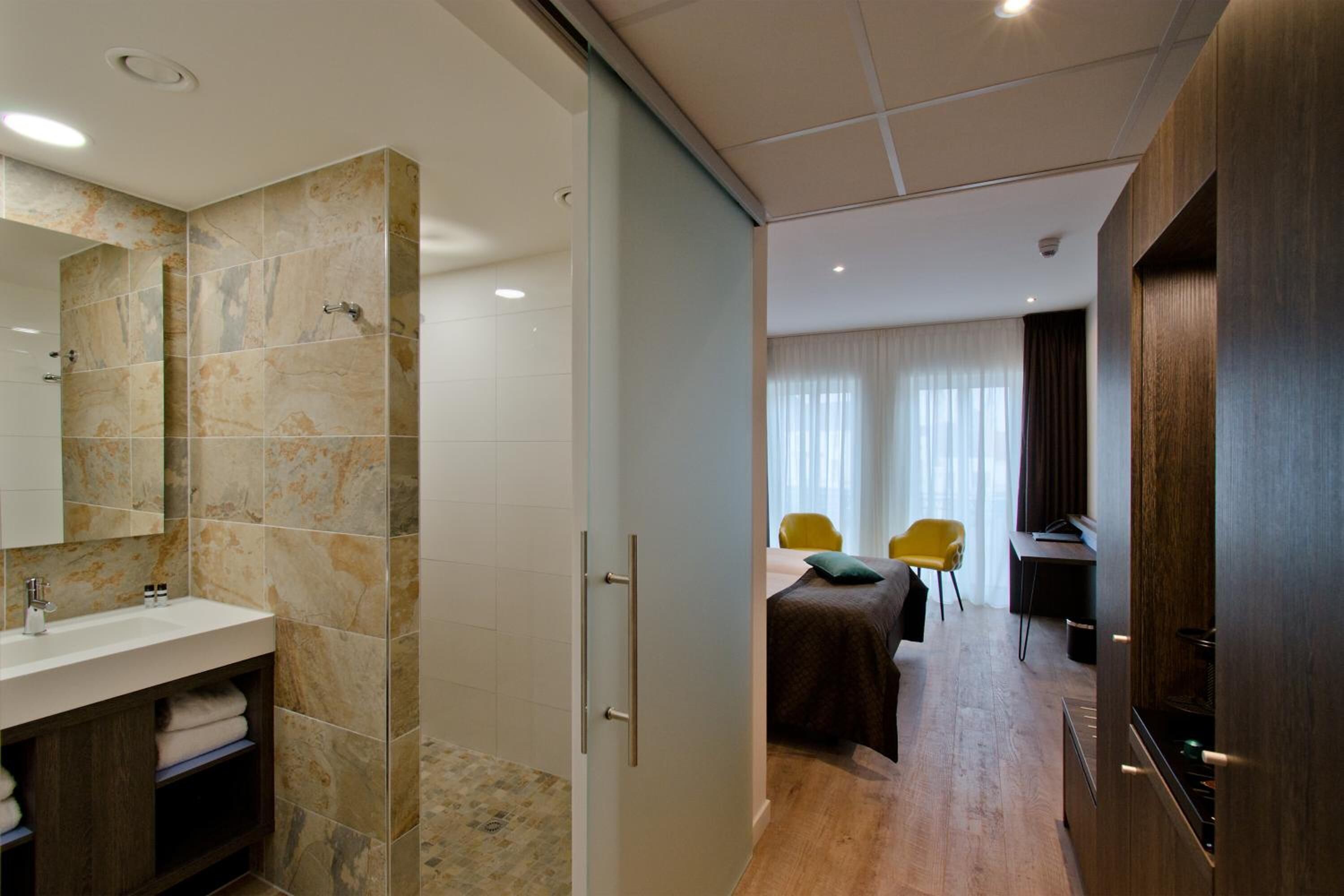 A modern bathroom with a large mirror, a sink, and a shower area.