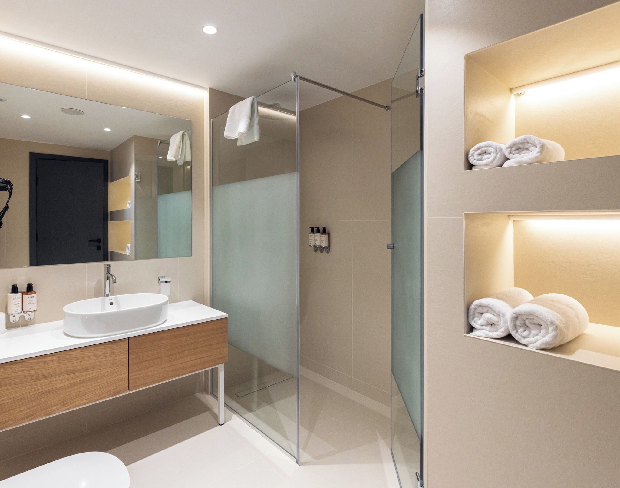 A modern bathroom with a glass-enclosed shower, a white sink, and a mirror.