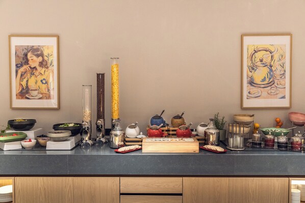 Una encimera de cocina con diferentes utensilios, como teteras, cuencos y un florero de vidrio.
