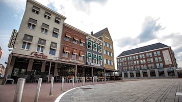 A hotel with a restaurant on the ground floor, multiple floors, and a paved plaza in front.