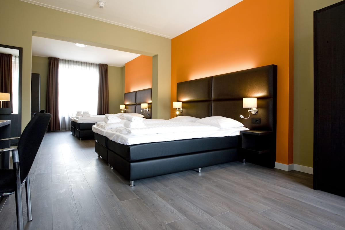 Una habitación de hotel moderna con una cama grande, mesitas de noche con lámparas, un escritorio y una silla.