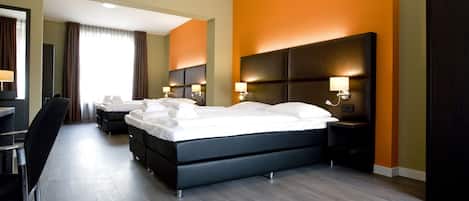 Una habitación de hotel moderna con una cama grande, mesitas de noche con lámparas, un escritorio y una silla.