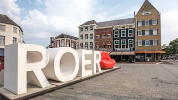 Een groot wit bord met de letters 'ROER' in een openbaar plein, met gebouwen op de achtergrond.