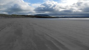A wide, open sandy beach with distant hills and a cloudy sky. - Sligo Bay Lodge (Rosses Point)