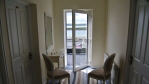 A hallway with a view of a body of water through a glass door, two chairs, a small table, and a radiator. - Sligo Bay Lodge (Rosses Point)