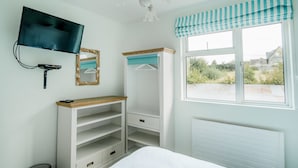 A bedroom with a bed, a TV, a wardrobe, and a window with a view of greenery. - Sligo Bay Lodge (Rosses Point)
