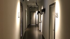 A long, narrow hallway with multiple doors, some with numbers above them, and overhead lighting fixtures. -  chic&basic Zoo (Barcelona)