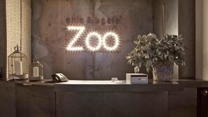 A reception desk with a sign reading "ZOO" and a potted plant. -  chic&basic Zoo (Barcelona)