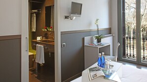 A hotel bathroom with a shower, toilet, sink, and a mounted television. -  chic&basic Zoo (Barcelona)