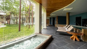 Un espacio de spa con hidromasaje, sillones de descanso y vistas al exterior.