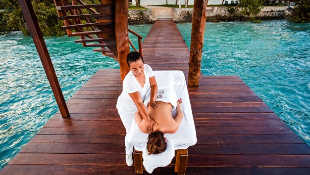 A wooden deck over water with a massage therapy session in progress.