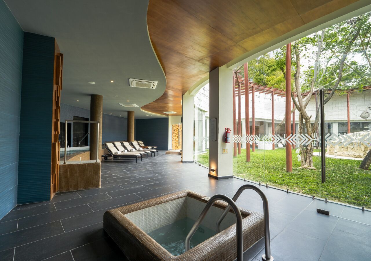 Uma área de spa moderna com hidromassagem, espreguiçadeiras e vista para o exterior.