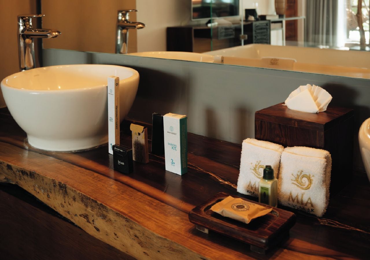 A bathroom vanity with a large white basin, a mirror, and various toiletries.