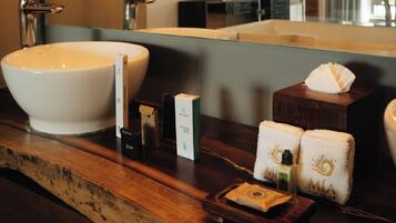 A bathroom vanity with a large white basin, a mirror, and various toiletries.