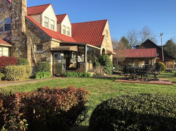 A stone building with a red roof, a covered patio, and a seating area with a table and chairs. - Phillips Historic Motel & Cottages (Robbinsville)