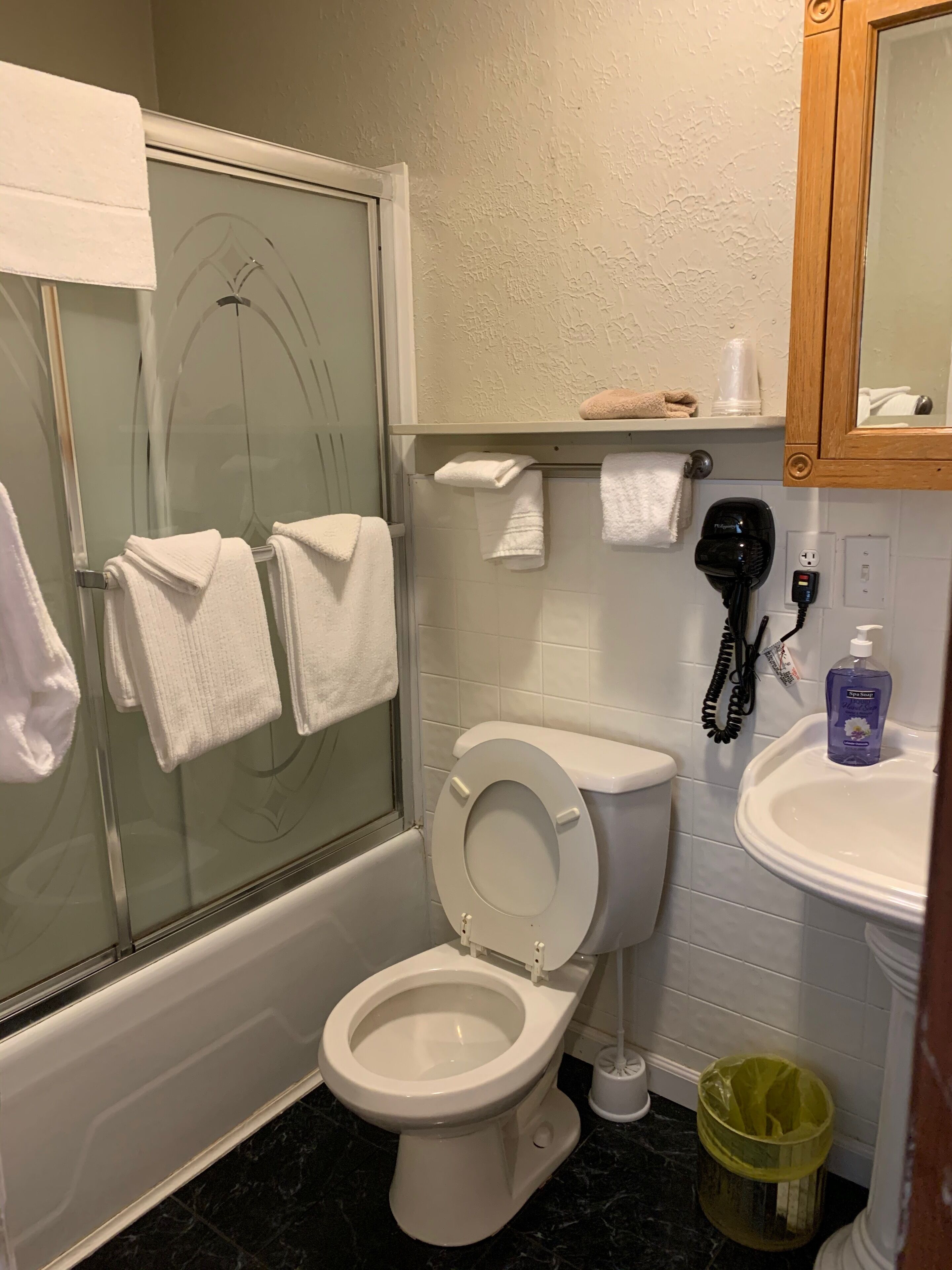Un baño con inodoro, cabina de ducha de cristal, lavabo y espejo.