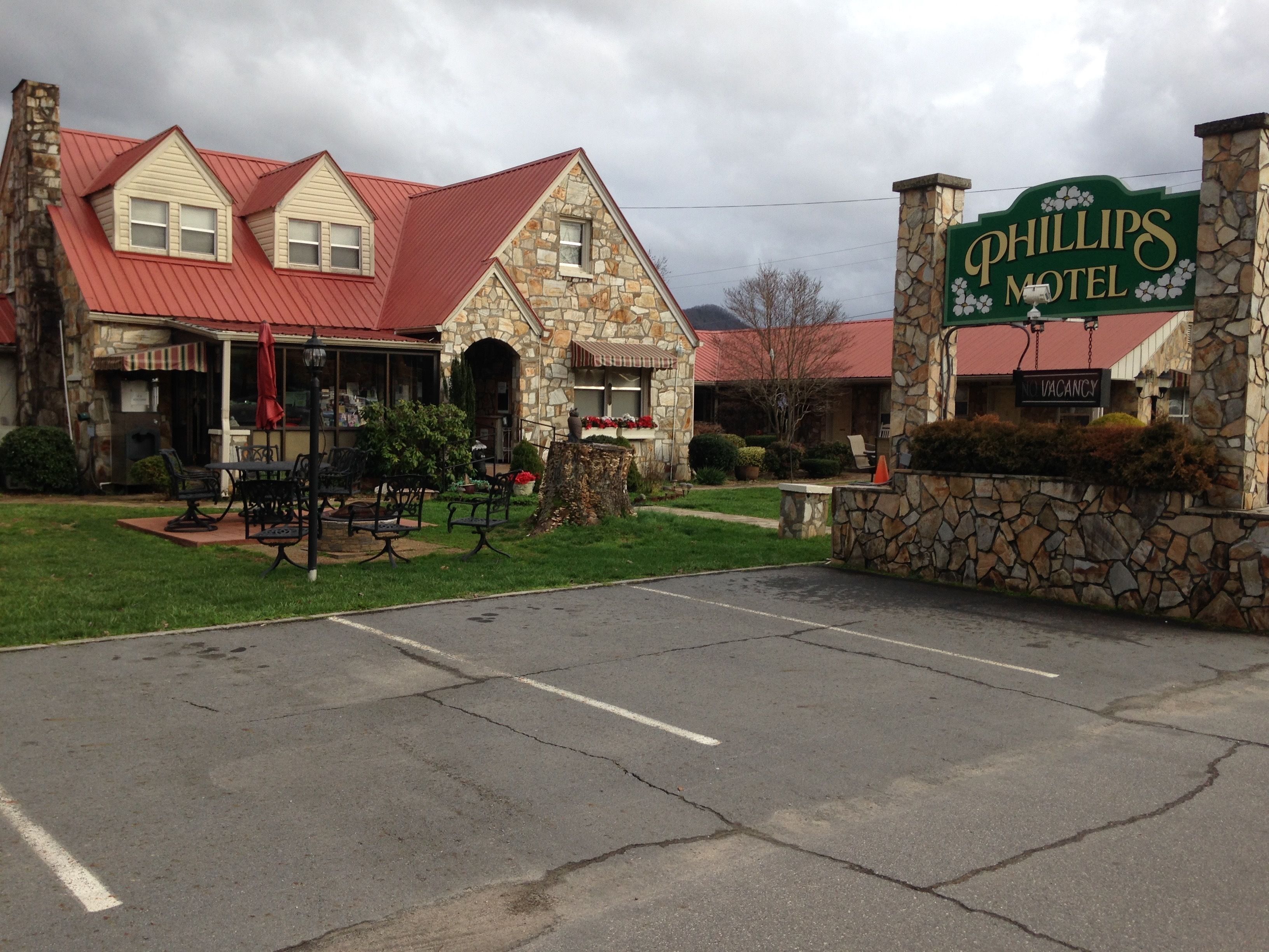 A stone building with a red roof, a sign reading "Phillips Motel", and outdoor seating.